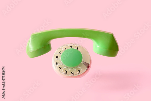 The handset and disc of an old retro phone on a pink background with the absence of the device itself. The concept of a minimal disappeared object. High quality photo