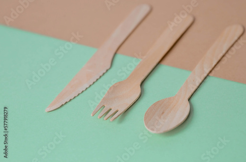 Eco-friendly disposable kitchen utensils on a beige-green background. Wooden forks, spoons and knives. Ecology, the concept of zero waste.