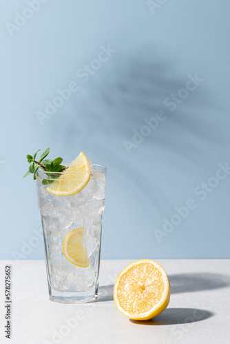 Refreshing drink with ice, lemon and mint. Cold lemonade on blue background