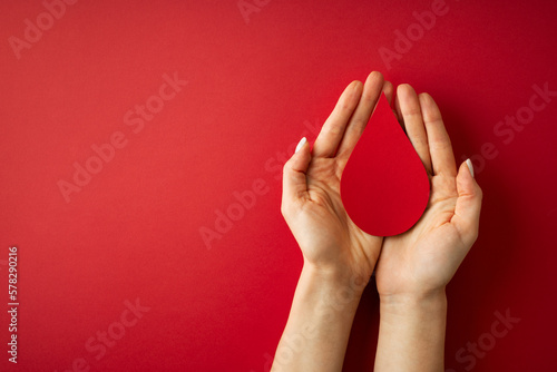 World donor day concept with hand holding paper red drop on white background