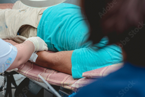 Applying clean dressing to a disinfected dog bite wound on the forearm of a patient while his worried wife looks on