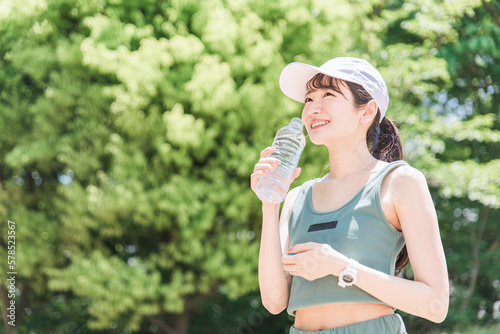 公園で水・ミネラルウォーターを飲む女性（水分補給・運動・ワークアウト・ランニング・ウォーキング） 