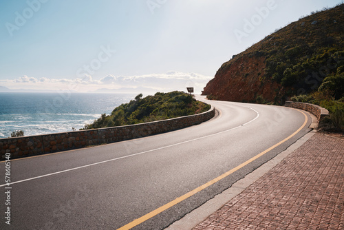 Mountain, road and ocean view with no people for travel, destination or sightseeing in Cape Town. Nature, beauty on empty street for road trip, vacation or holiday on South Africa blue sky background