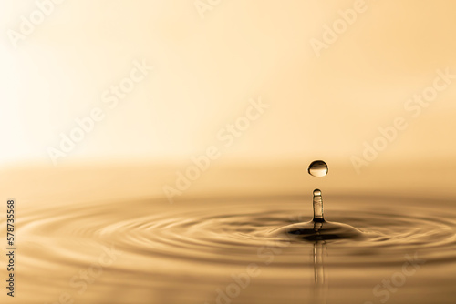 Water drop. Transparent water drop with circular waves. Slightly blurred golden yellow splattered water droplets. natural water drop concept and use it as a background.