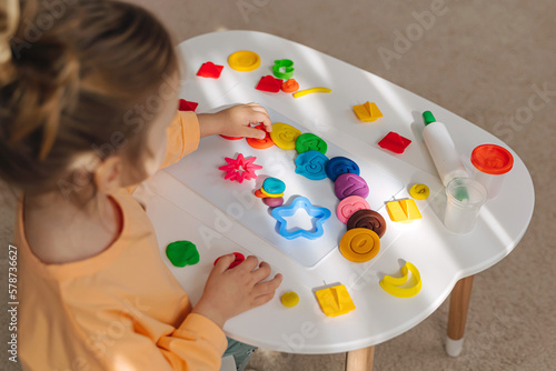A little girl play with plasticine and creates colorful numbers. Learning to count through play. Early education. Fine motor skills, creativity and hobby.