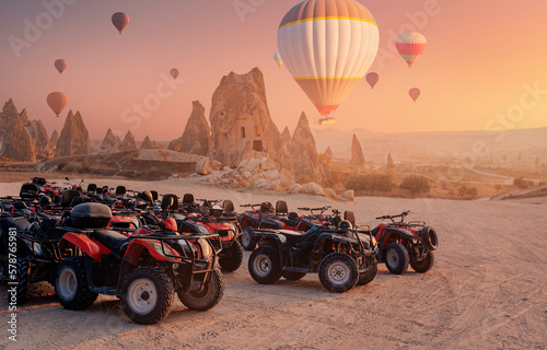 ATV trip quad bike in Cappadocia with set colorful hot air balloon fly in sky with sunset. Concept tourist travel Goreme Turkey