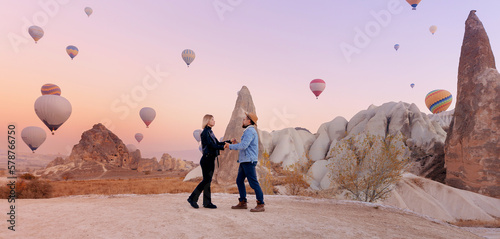 Loving couple hugging against background of hot air colorful balloons, romantic honeymoon in Cappadocia Turkey. Banner Travel photo tourist