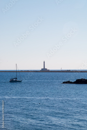 Faro de la isla de Sant' Andrea desde el casco antiguo de Gallipoli, Italia. Paisaje a contra luz con un velero navegando junto al faro y las otras islas.