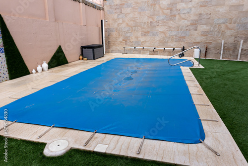 Small pool covered with a blue tarpaulin during the winter season to cover it and prevent dirt.