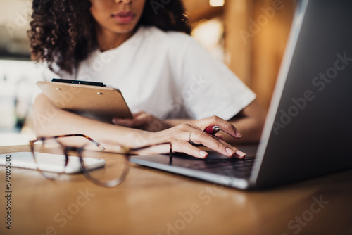 Crop black woman working on laptop in cafe