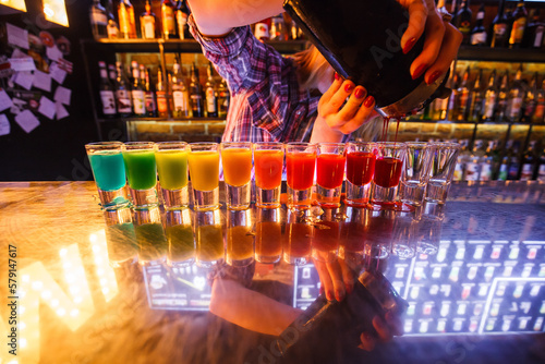 Dozen of colorful rainbow cocktails being prepared on the counter by a bartender in Gdansk, Poland