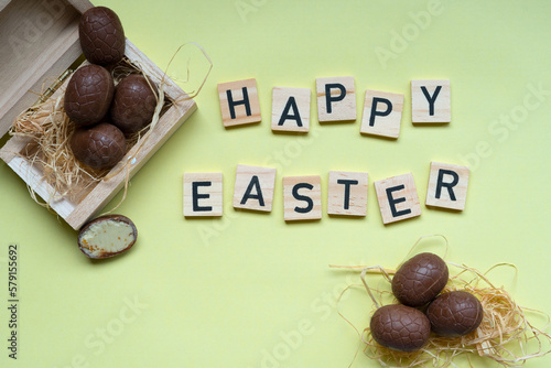 wesołych świąt napis na żółtym tle z dekoracją czekoladowego jajka wielkanocnego, wielkanoc