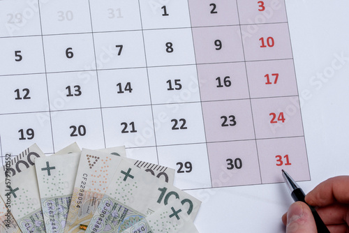 Kalendarz z długopisem trzymanym w dłoni wskazujący na ostatni - 31 dzień miesiąca 