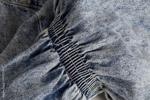 Cinched fabric detail. Blue bleached denim material.