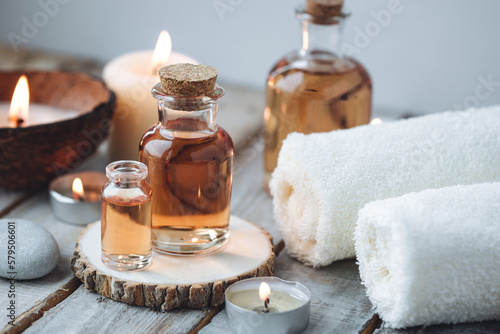 Concept of spa treatment in salon with pure organic natural oil. Atmosphere of relax, detention. Aromatherapy, candles, towel, wooden background. Skin care, body gentle treatment