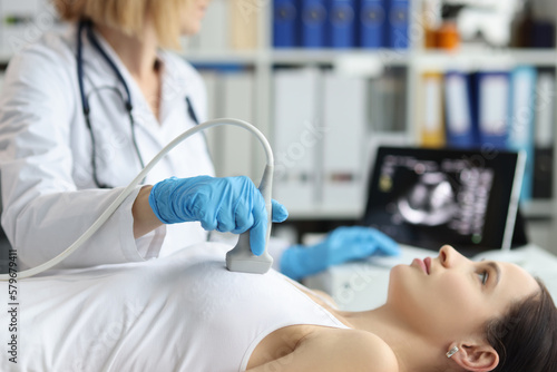 Doctor holds ultrasound probe on chest of patient in clinic closeup