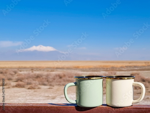 Two enameled cups of coffee or tea in the autumn landscape outdoors.Two enamel mugs in the foreground, beautiful view of the snowy mountain erciyes. Copy space for text.