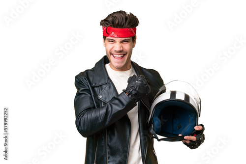 Young caucasian man with a motorcycle helmet over isolated background celebrating a victory