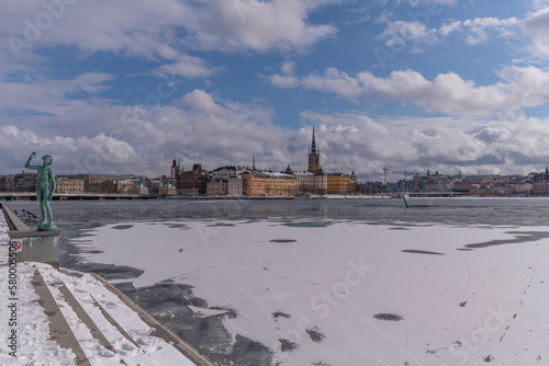 View from the Town City Hall parterre over the bay Riddarfjärden with ice floes, tourist, and the old town islands, a snowy day in Stockholm
