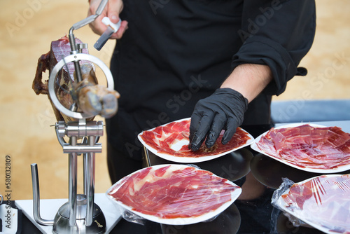 Detail of the hand of a professional Iberian ham cutter placing the slices on a plate. Concept pork, food, ham, iberian, spain, denomination of origin.