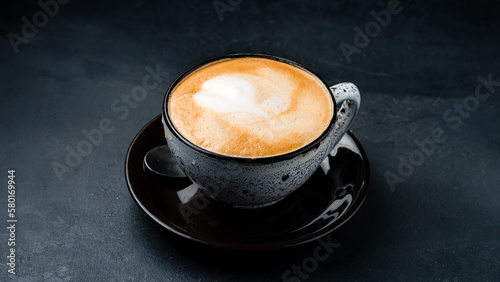 A cup of hot cappuccino coffee on black background.