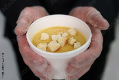Cook holds white bowl of cream soup with croutons and mushrooms