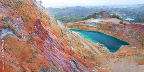 Abandoned copper mines of Cyprus. Colorful gossan (iron cap) of Alestos mine with open pit filled with water, and Memi mine lake at the distance