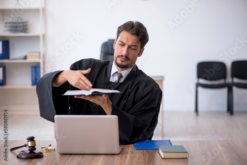 Young male judge reading book in the courthouse