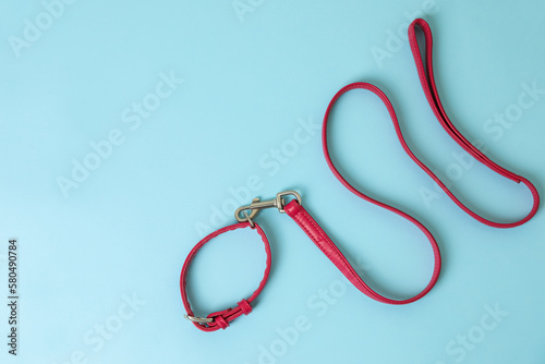 Red leather dog leash on light blue background, top view. Space for text