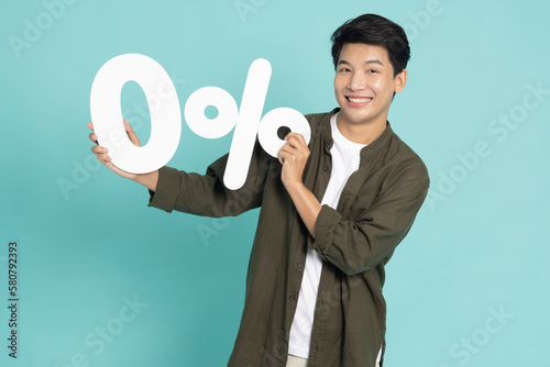 Portrait of Asian man showing and holding 0% number or zero percent isolated over light green background