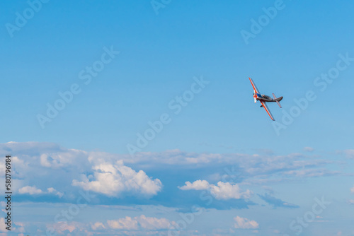 Small retro airplane, light aircraft flying in blue cloudy sky and doing stunts at Air Show. Performance, extreme, aerobatic and sport concept