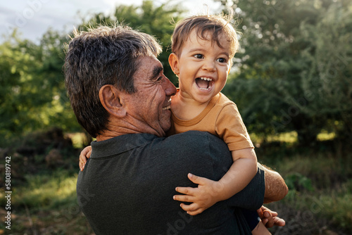 Playful grandfather spending time with his grandson in park on sunny day