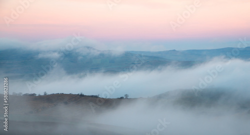 Landscape with the silhouette of the hills in the morning fog