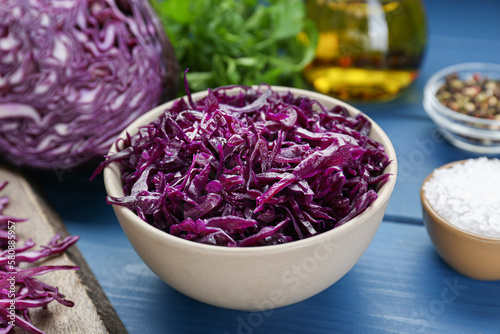 Tasty red cabbage sauerkraut and different ingredients on light blue wooden table