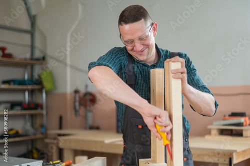 Caucasian man assembling a table with a screwdriver. 