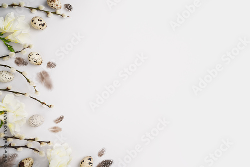 Eco Easter template. Pussy willow branches, freesia flowers, feathers and natural quail eggs on light grey background. Festive composition layout. Spring holiday. Top view, flat lay, copy space.