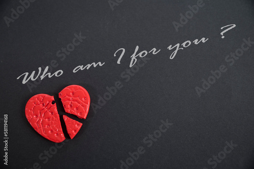 Złamane czerwone serce na czarnym tle z napisem "Who am I for you".