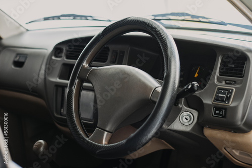 Black classic car interior. Steering wheel, speedometer, display and multimedia dashboard. Detail of car interior inside. Manual gear stick.