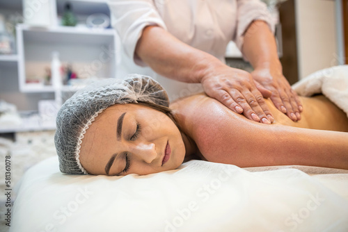 beauty client receives physical therapy from masseuse on shoulders and back in beauty spa.
