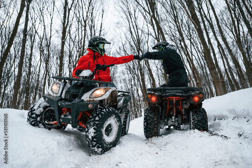 Knocking the fists. Two people are riding ATV in the winter forest