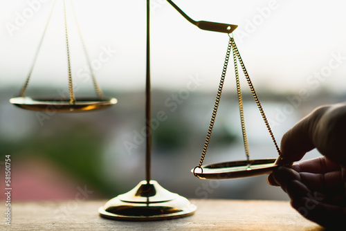 Tip the scales of justice concept as a the hand of a person illegally influencing the legal system for an unfair advantage. 