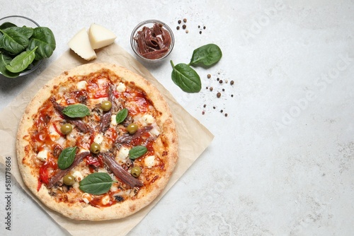Tasty pizza with anchovies and ingredients on white table, flat lay. Space for text