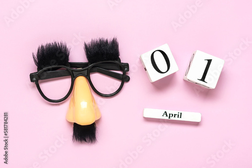 funny face - fake eyeglasses, nose and mustache, calendar with date 01 April on pink background Happy fools day concept 1st April party Holiday greetind card