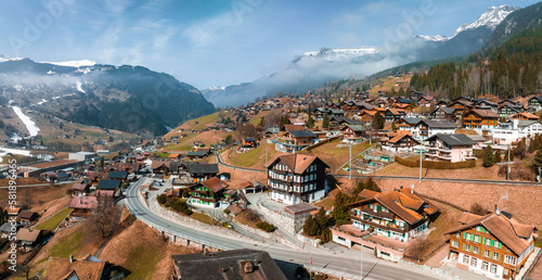 Aerial panorama of the Grindelwald, Switzerland village view near Swiss Alps mountains panorama landscape, wooden chalets on green fields and high peaks in background, Bernese Oberland, Europe.