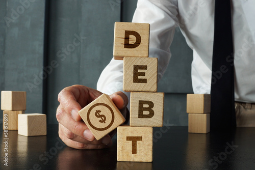 Debt is shown by wooden blocks with the word and the image of dollars. Payment of taxes and of debt to the state. Concept of financial crisis and problems. Risk management. Debt exemption and loan