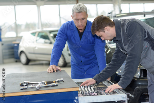 teacher and student choosing appropriate tools in mechanic school