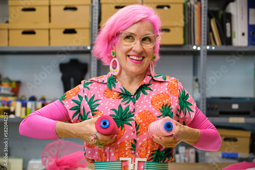 Dressmaker with colorfull clothes making funny faces with sewing thread reels.