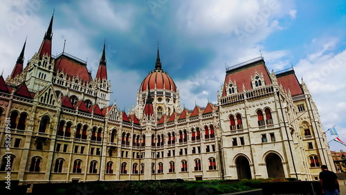 Orszaghaz, Budapest, Hungary - June 5, 2018: exterior of the side of the Hungarian Parliament Building under a cloudy sky with the Hungarian flag