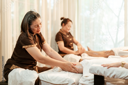 Masseuse mature asian woman working massage service in spa salon, Foot and leg massage customer. Relaxing massage in spa salon concept.