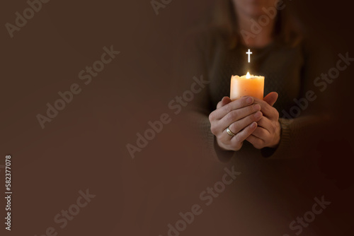 Kobieta modli się trzymając w dłoniach zapaloną świecę. Zmartwychwstanie pańskie wiara i nadzieja w modlitwie